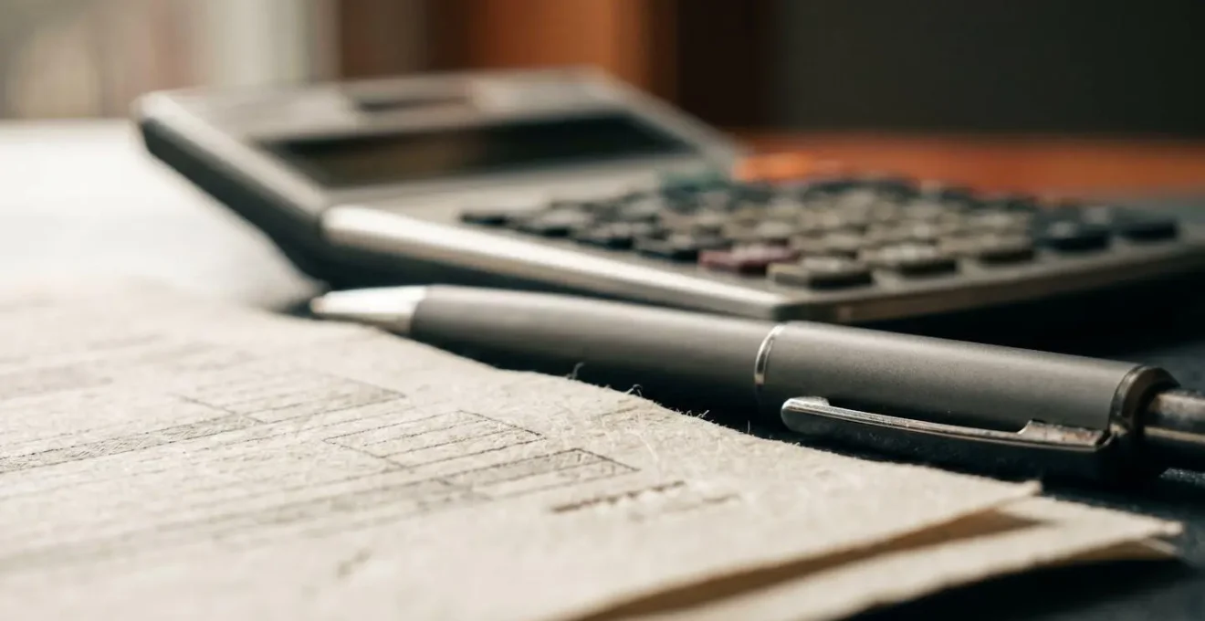 Vue macro de documents financiers avec calculatrice et stylo dans une lumière naturelle